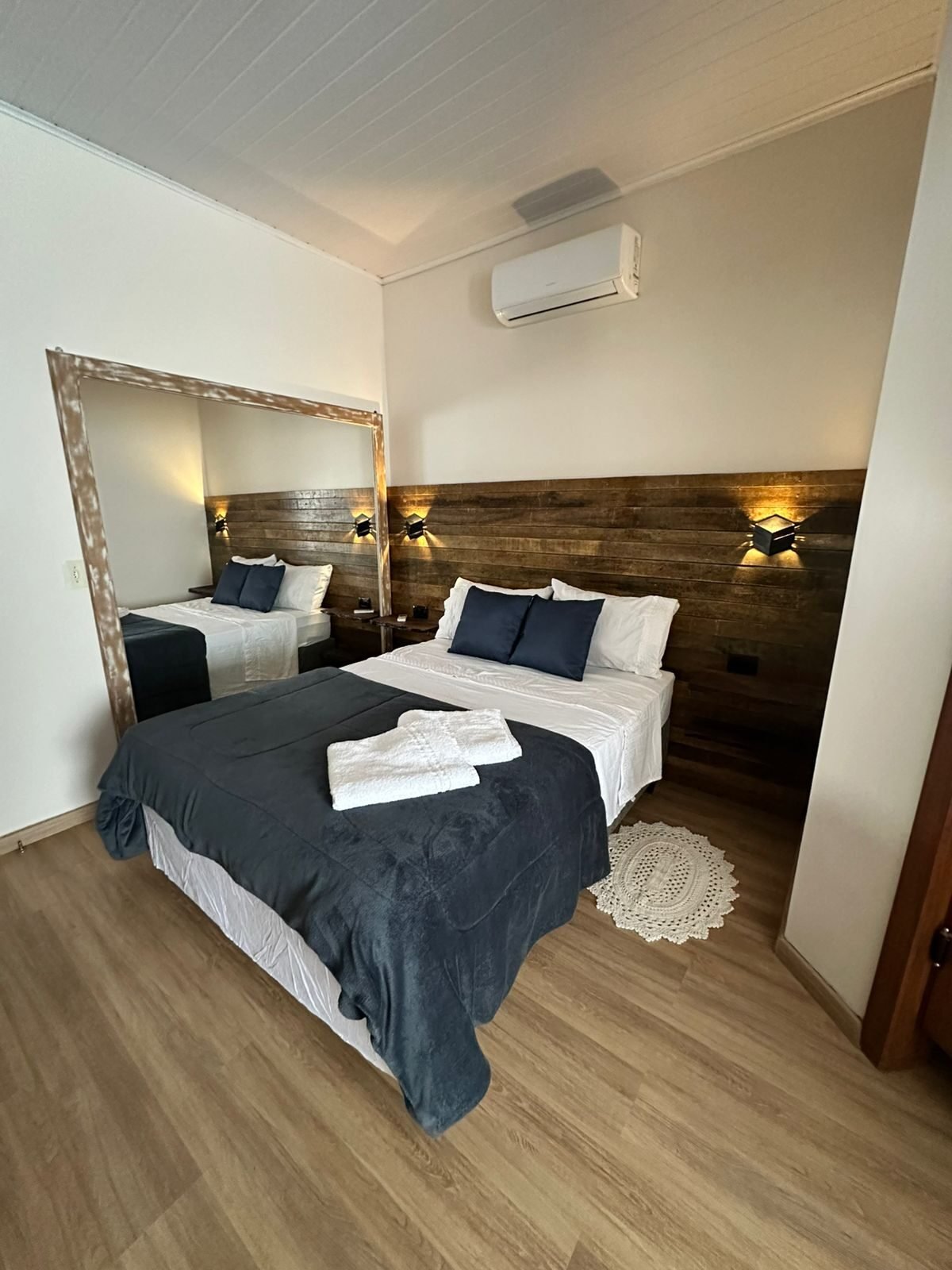 Sala com sofá amplo e televisão em painel de madeira